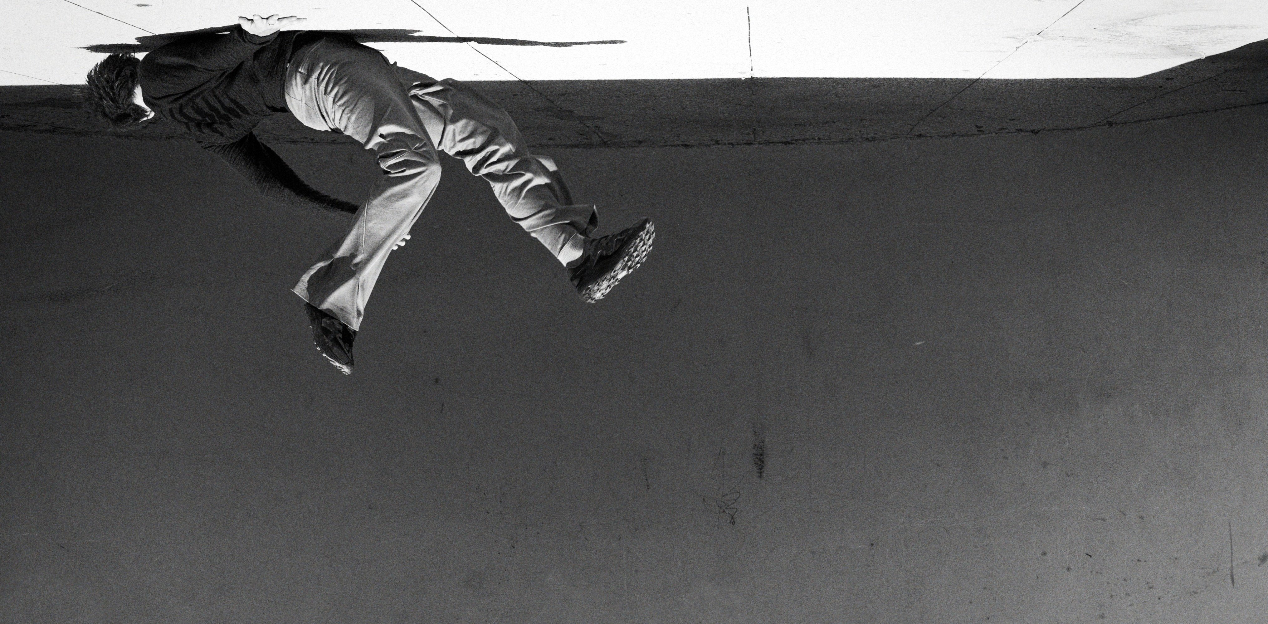 A person wearing Merrell 1TRL shoes leaping against a concrete wall.